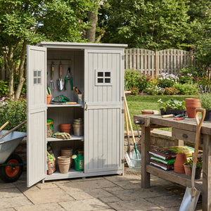 Outdoor storage shed filled with gardening tools and supplies in a garden setting.